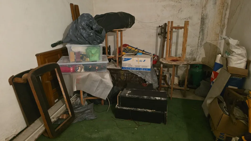 Móveis usados, cadeiras e caixas numa garagem